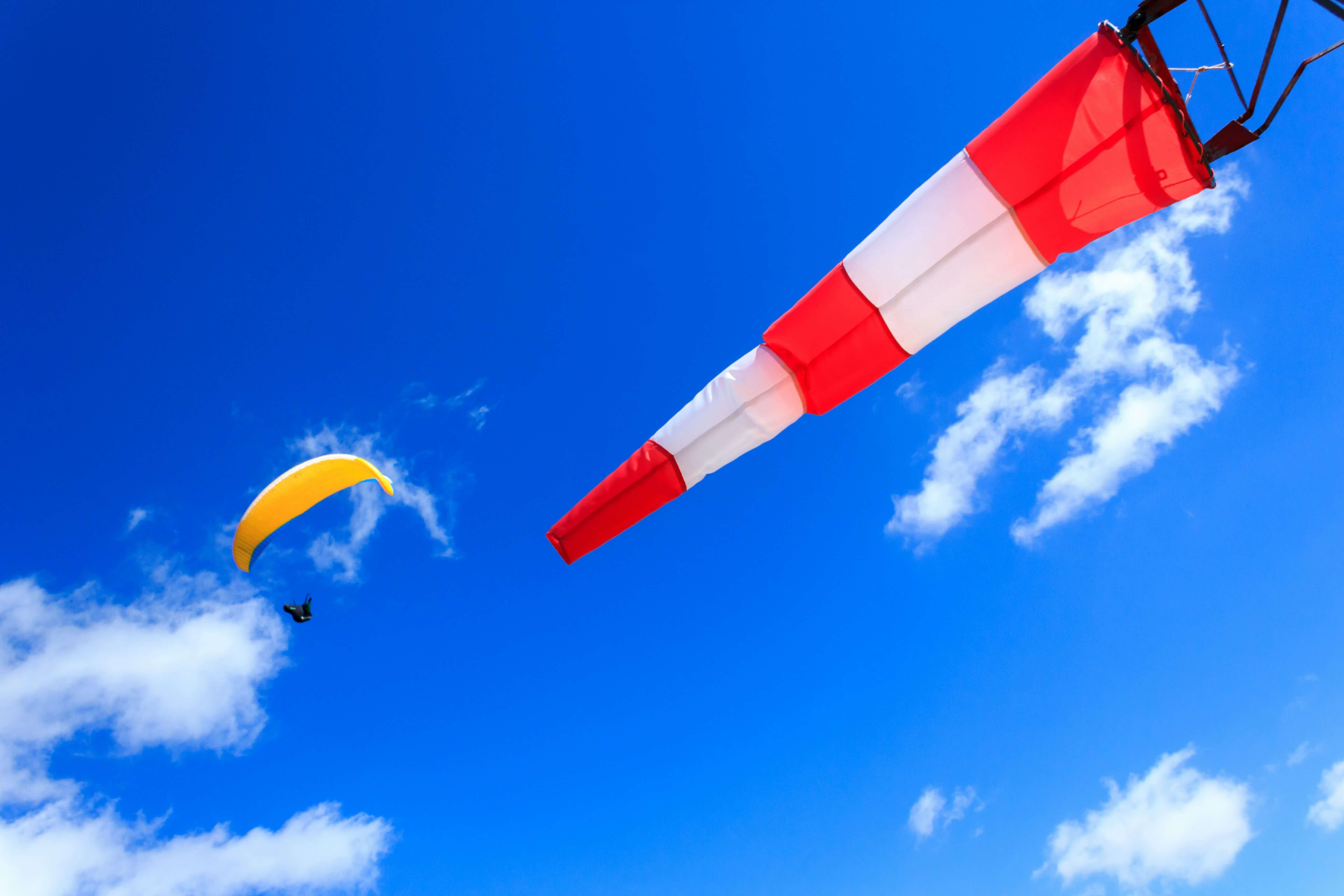 a windsock blowing while a person parasails over it