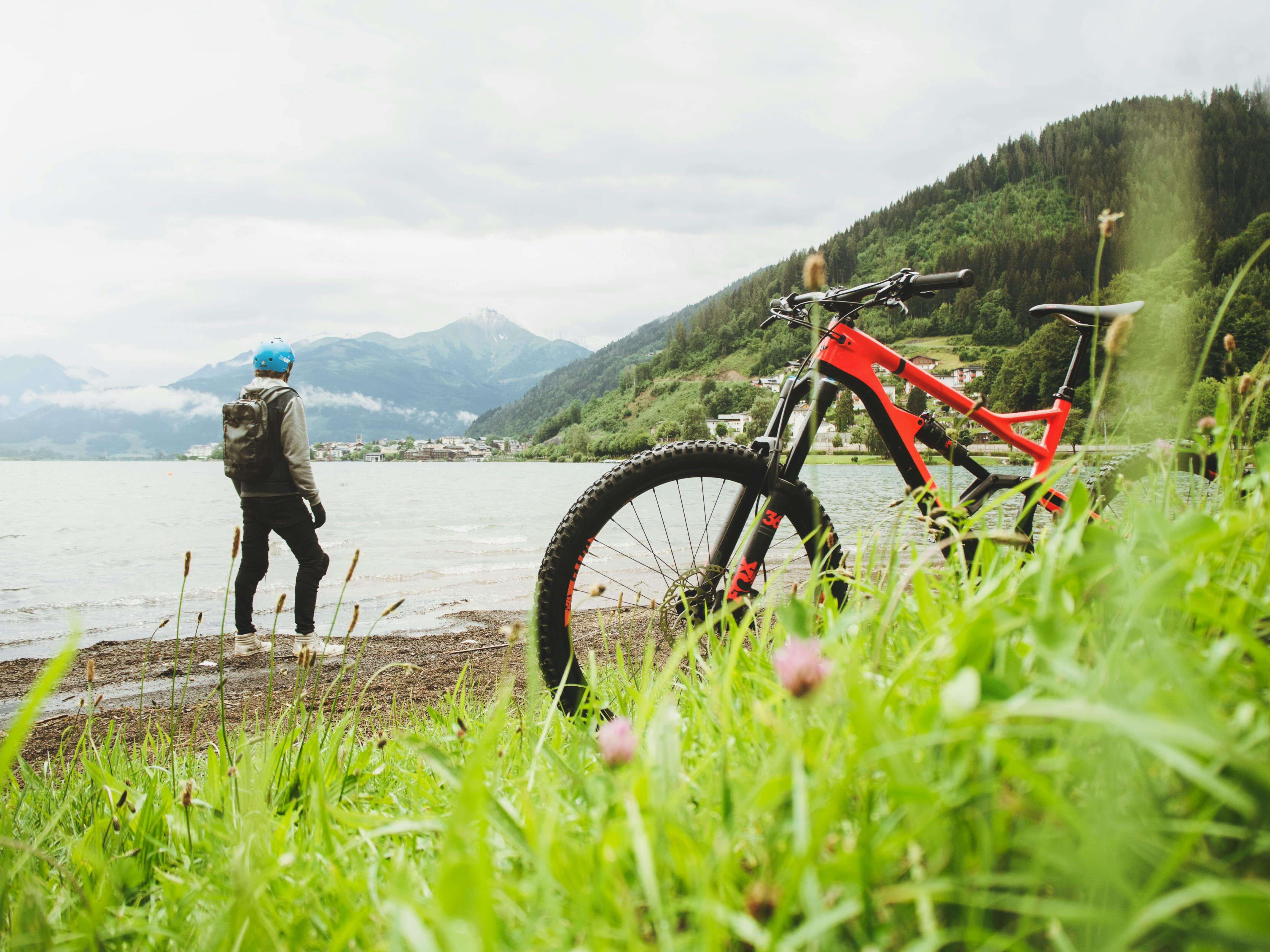 a red bike with a biker who is admiring a lake