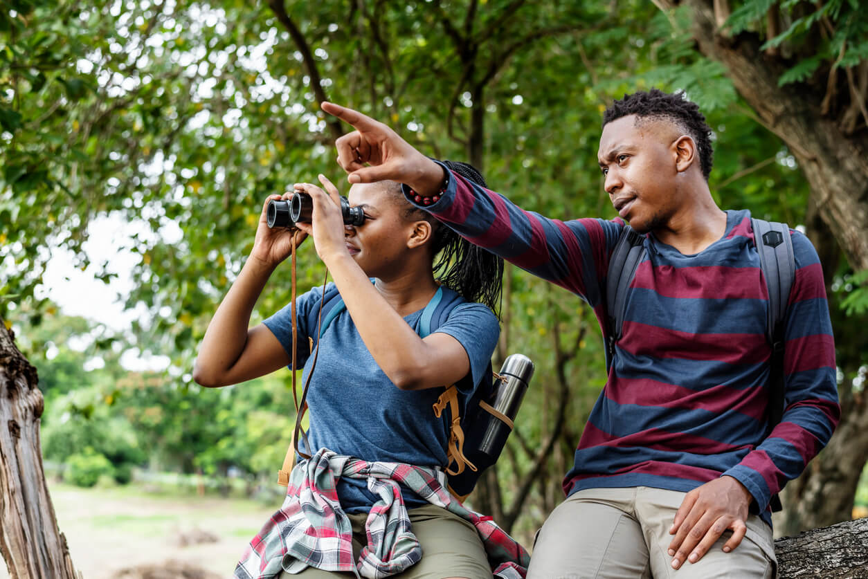 two young adults birdwatching in the forest